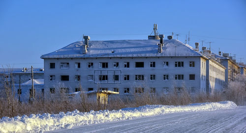 Snow covered buildings against clear blue sky