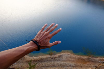 Cropped hand reaching lake