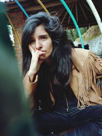 Portrait of young woman sitting outdoors thinking