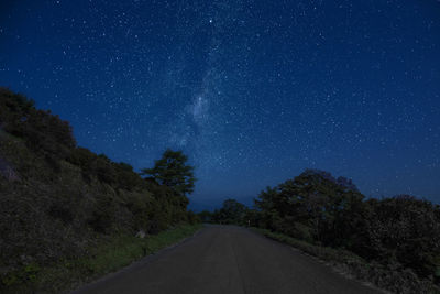 Road amidst trees against sky at night