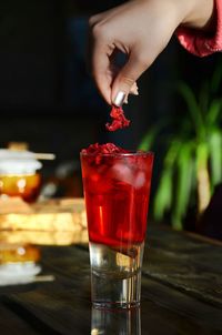 Close-up of hand holding drink on table