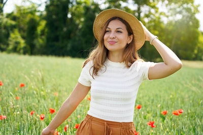Girl with hat walking in a field with red flowers. summer landscape. warm colors. 
