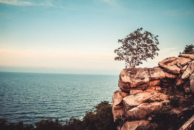 Rock formation by sea against sky