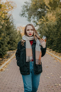 Portrait of beautiful young woman standing on footpath