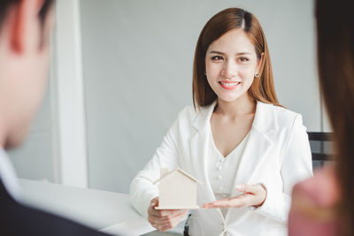 Smiling businesswoman showing model home to colleagues in office