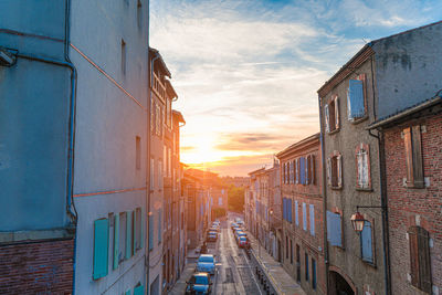 Street amidst buildings against sky during sunset