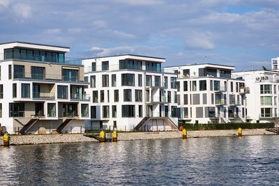 Buildings by river against sky in city