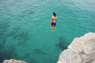 Full length rear view of shirtless man in sea