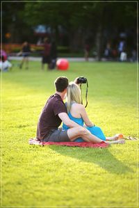 Rear view of couple taking selfie from camera on field