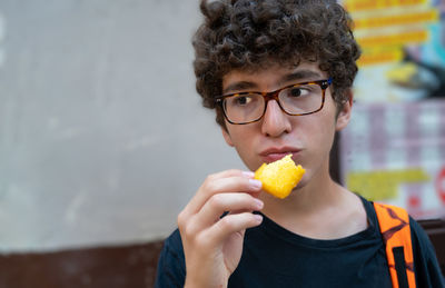 Teenage boy wearing eyeglasses eating snacks