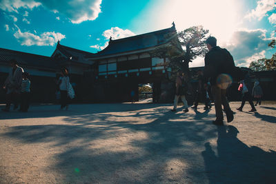 People standing by buildings in city against sky