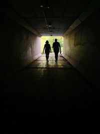 Rear view of silhouette people walking in tunnel