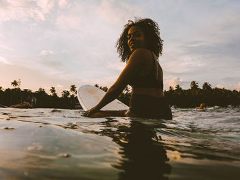 Side view of woman against sky at sunset