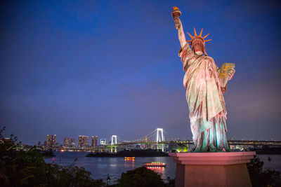 Statue of bridge over river against sky