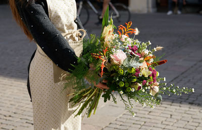 Low section of person holding flowering plant