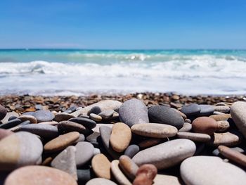 Close-up of pebbles on beach against blue sky