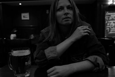 Midsection of young woman with beer glass while sitting at home