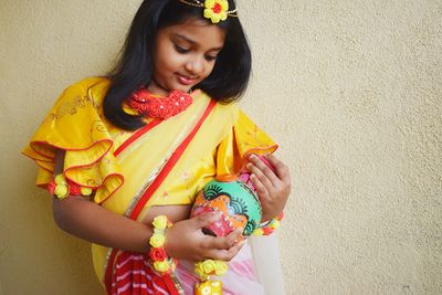 Portrait of smiling girl standing against wall