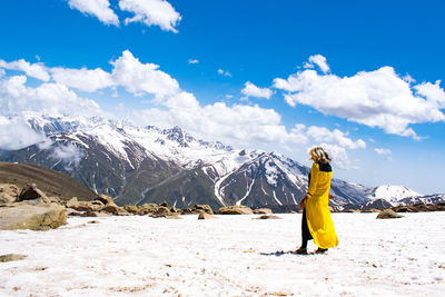Rear view of woman standing on mountain against sky