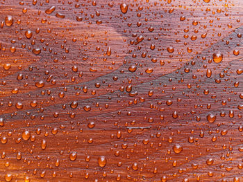 Full frame natural background with rain drops on red wooden table