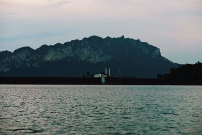 Scenic view of sea by mountains against sky