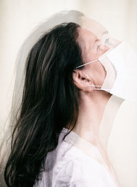 Multiple exposure image of woman wearing mask looking away against white background