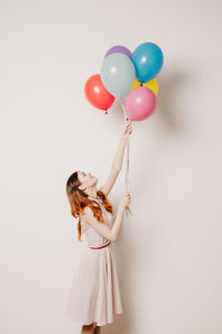 Woman holding colorful balloons against white background