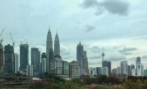 Low angle view of skyscrapers against cloudy sky