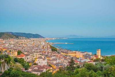 Aerial view of townscape by sea against clear sky