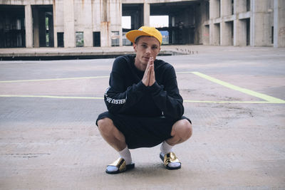 Full length portrait of man crouching on street