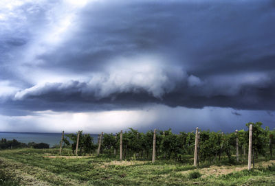 Scenic view of field against storm clouds