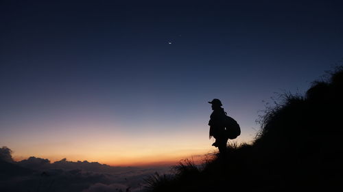 Silhouette man standing on mountain against sky during sunset