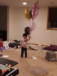 Rear view of girl with balloons at home