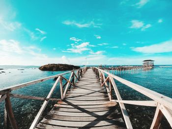 Empty pier over sea against sky