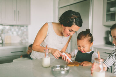 Daughter looking at mother icing cookies