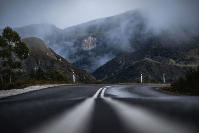 Road leading towards mountains against sky