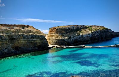 Rock formation by sea against blue sky