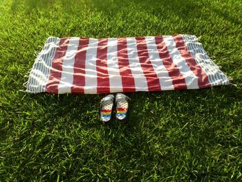 Close-up of footwear and picnic blanket on grassy field at public park