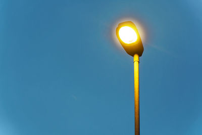 Low angle view of illuminated street light against blue sky