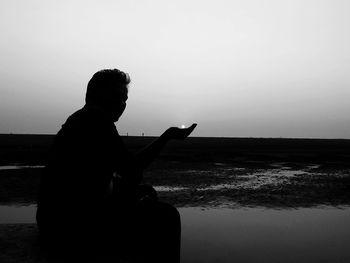 Side view of silhouette man overlooking calm sea