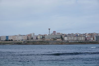 Sea by buildings against sky in city