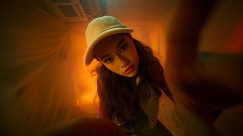 Portrait of young woman standing against orange sky