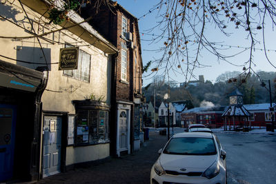 Cars on street by buildings against clear sky