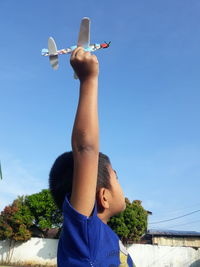 Full length of girl with arms raised against blue sky