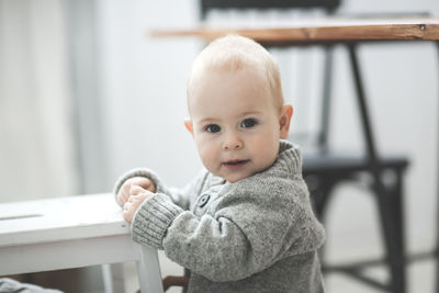 Portrait of a baby of 10 months in a knitted gray sweater, the concept of childhood and safety. 