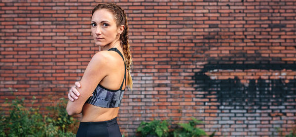 Full length of woman standing against brick wall