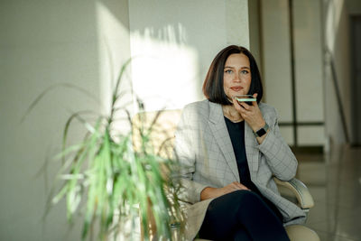 Smiling woman holding phone having call. businesswoman records voice message in mobile app online.