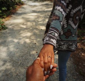 Cropped image of man holding woman hand on walkway