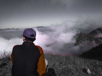 Rear view of man sitting against mountains