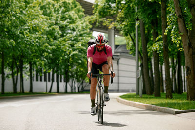 Rear view of man riding bicycle on road